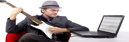 Man playing his guitar following the notes form his laptop